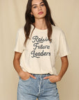 Model wearing bone colored shirt with retro dark gray font that reads "Raising Future Leaders"