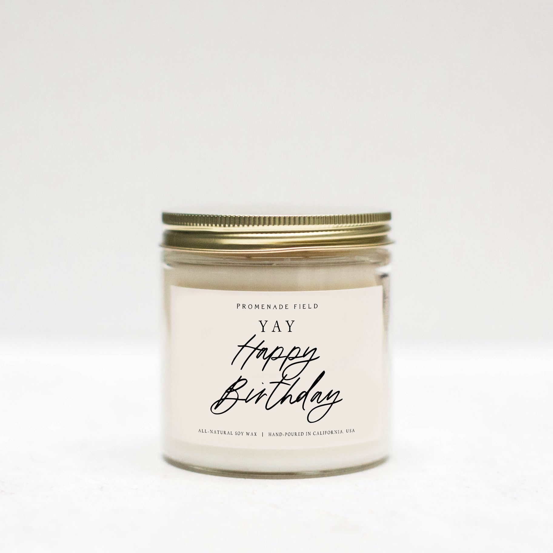 Jar candle with gold lid, white label says "Yay Happy Birthday" in cursive font.