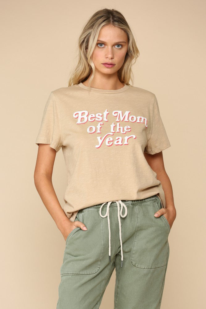 Model wearing sand colored tee with a bold retro style print with pink and white font that reads &quot;best mom of the year&quot;