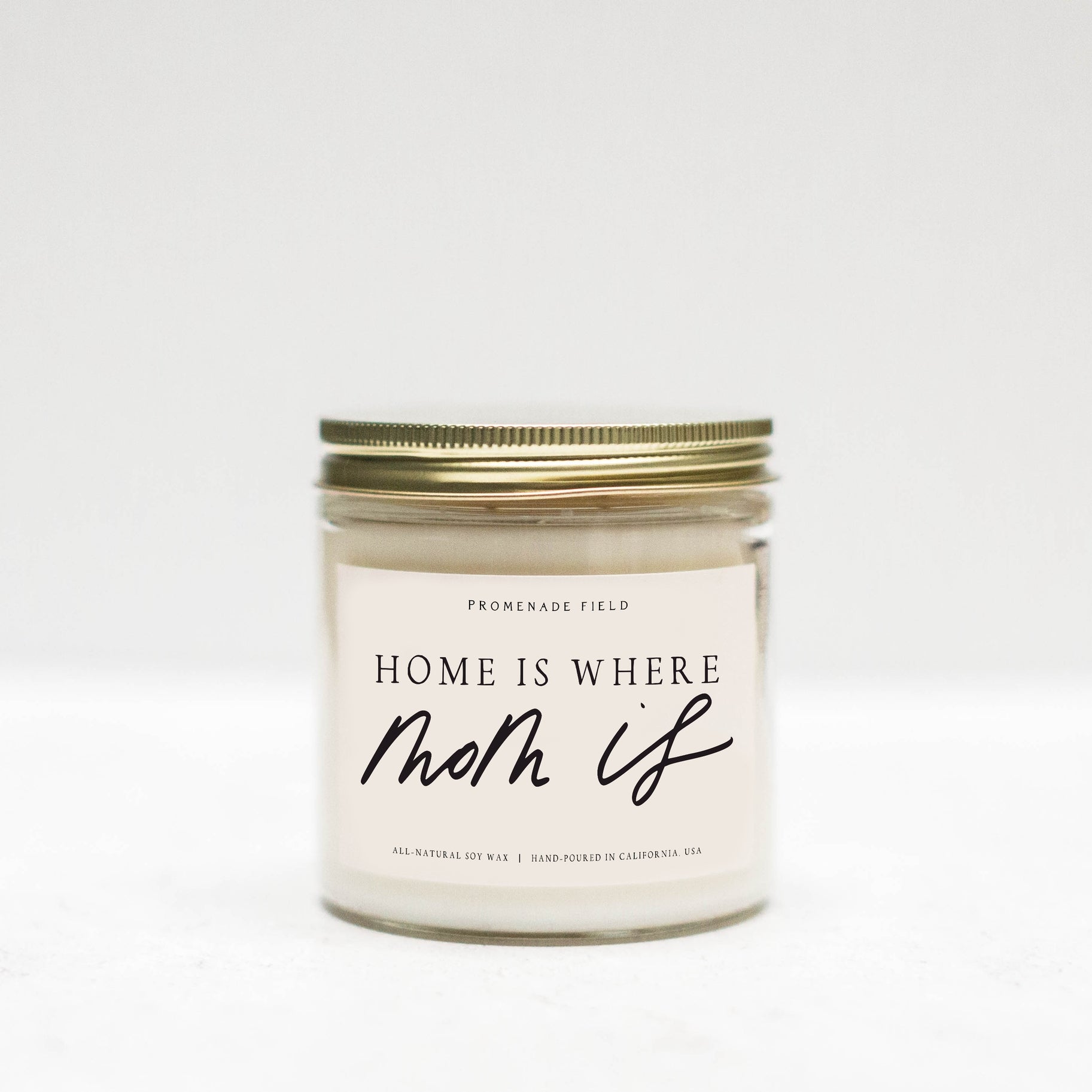 Jar candle with gold lid, white label says "Home is where Mom Is" in cursive font.