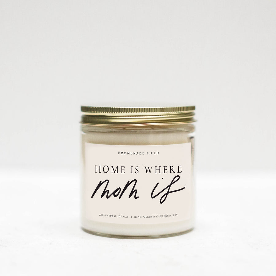 Jar candle with gold lid, white label says "Home is where Mom Is" in cursive font.