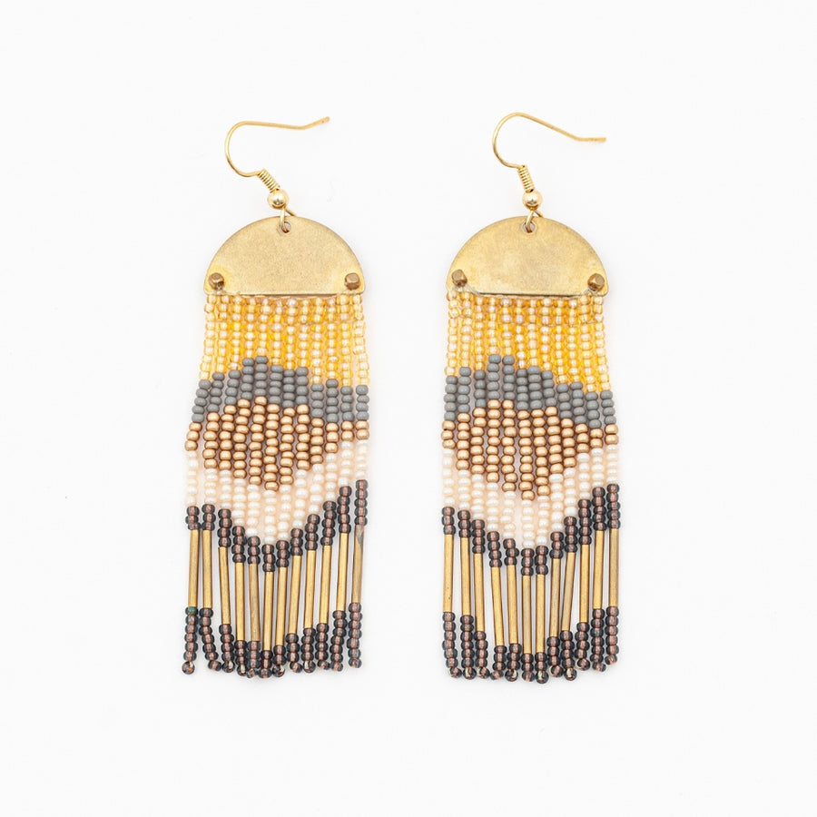 earrings with a hook, brass half moon  with curved side facing up and descending fringe in colorful layer: gold, grey, bronze, cream, a dark grey/blue color and long gold beads forming an abstract design in the beading